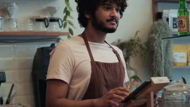 Positive Curly Haired Indian Male Barista Working Cash Register Cafe — Stockvideo