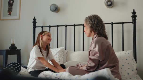 快乐的灰白头发的妈妈穿着睡衣坐在床上和女儿说话 — 图库视频影像