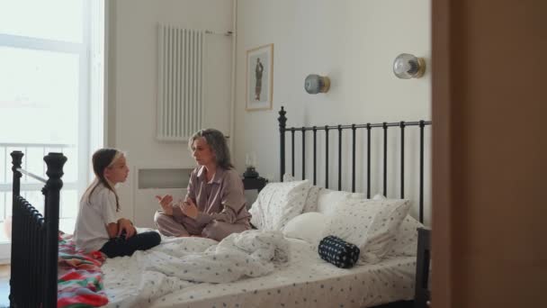 Сконцентрированная Седовласая Мама Разговаривает Своей Дочерью Сидящей Пижаме Кровати Утром — стоковое видео