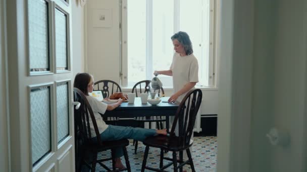 Hija Mirando Tableta Antes Desayunar Con Joven Mamá Confiada Cocina — Vídeo de stock