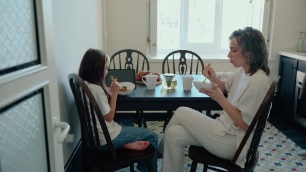 Hija Pensativa Desayunando Con Joven Mamá Pelo Gris Cocina — Vídeo de stock