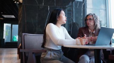 Laptop üzerinde çalışan ve ofiste konuşan çok kültürlü kadın iş arkadaşları.