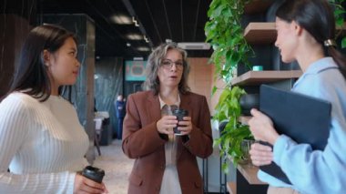 Kahve molasında konuşan çok uluslu iş kadınları.