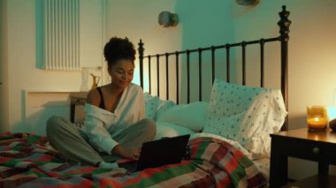 Pozitif Afrikalı kadın akşamları laptopla evdeki yatakta konuşuyor.