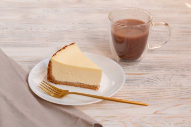 Bir parça cheesecake New York ve altın çatallı bir fincan kakao..