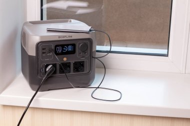 VINNYTSIA, UKRAINE - 17 Temmuz 2024: Kesintisiz Güç Kaynağı. Elektrik prizi ve şarjlı bir telefonla elektrik kesintileri sırasında ev için yedek seçenek