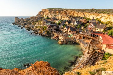 Anchor Bay, Mellieha, Malta 'daki ünlü Temel Reis Köyü. Turkuaz deniz suyu ve mavi gökyüzü.