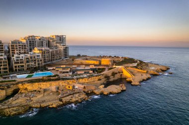 Günbatımında Malta 'daki Sliema sahil beldesi, mavi okyanus suları, hava aracı manzarası.