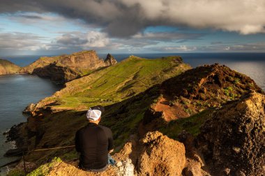 Portekiz, Madeira 'daki Vereda da Ponta do Sao Lourenco' da yürüyüş davasında oturan maceraperest.