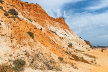 Güneşli bir günde Portekiz, Algrave 'deki kumlu sahilde kızıl kayalıklar