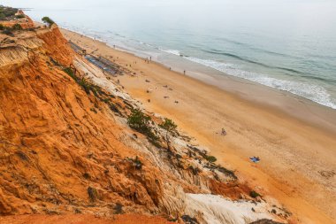 Güneşli bir günde Portekiz, Algrave 'deki kumlu sahilde kızıl kayalıklar
