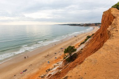 Güneşli bir günde Portekiz, Algrave 'deki kumlu sahilde kızıl kayalıklar