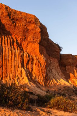 Algrave, Portekiz 'deki kumlu sahilde gün batımında kızıl kayalıklar