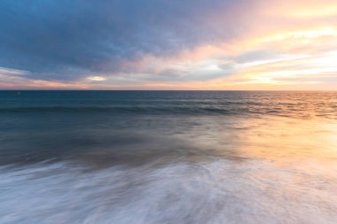 Portekiz 'de kumlu plajlı okyanus günbatımında bulutlu manzara ve deniz manzarası