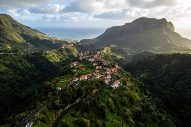 Madeira Adası manzarası, tepelerdeki küçük köy ve yeşil yemyeşil orman. Hava aracı görüntüsü. Portekiz seyahati.