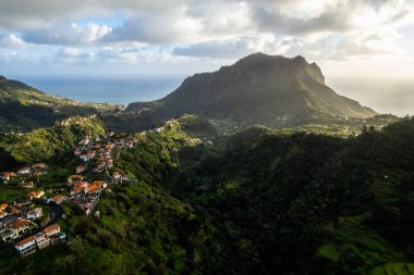Madeira Adası manzarası, tepelerdeki küçük köy ve yeşil yemyeşil orman. Hava aracı görüntüsü. Portekiz seyahati.