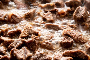 Yakın plan güzel büyük et parçaları ve tavada soğan.