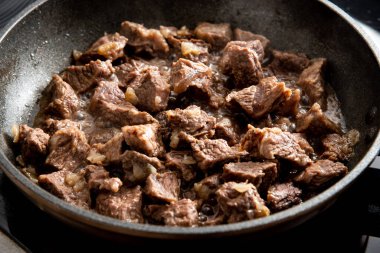 Yakın plan güzel büyük et parçaları ve tavada soğan.