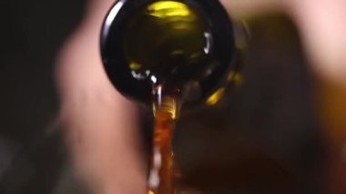 Yeşil bir cam şişeden koyu bir zemin üzerine dökülen kırmızı sıvı yakın plan. Dramatik renk karşıtlığı akışkan hareket ve dokuyu vurguluyor.