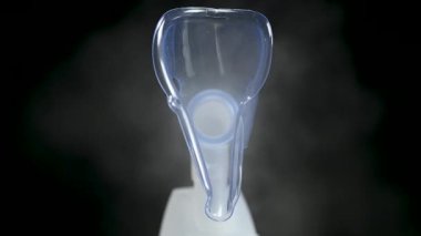 Siyah arka planda nebulizör maskeli buharlaştırıcı. Tıbbi cihaz. Soğuk algınlığı tedavisi. Macro, kapat.