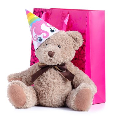 Parti şapkalı oyuncak ayı ve beyaz arka planda kalpleri olan pembe hediye çantası.