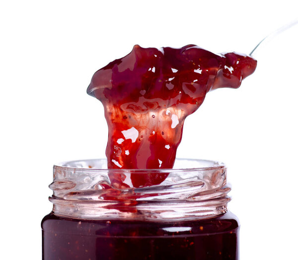 Open jar of strawberry jam and a spoon on white background isolation, close up