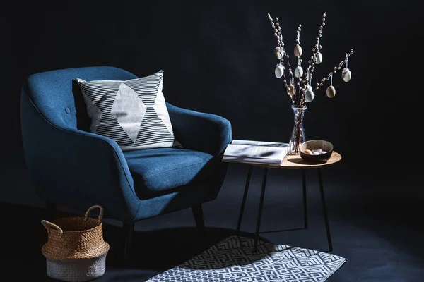假日和家居装饰概念 现代蓝色椅子 有枕头 篮子和东方蛋 挂在深色房间桌子上的柳枝上 — 图库照片