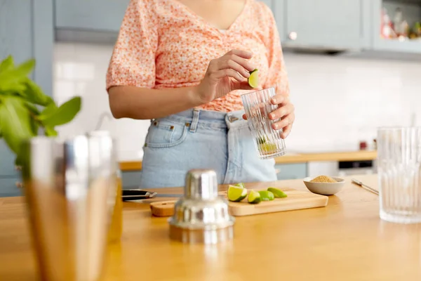 ドリンクと人のコンセプト 家庭のキッチンでライムモヒートカクテルを作るガラスの女性のクローズアップ — ストック写真