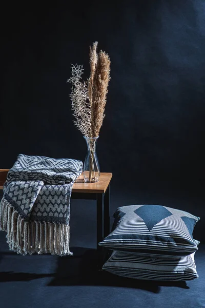 室内装饰和家居装饰概念 在长椅上的花瓶里放毛毯和干植物 在黑暗的房间里放枕头在地板上 — 图库照片