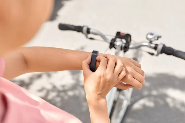 people, leisure and sport - close up of woman with smart watch riding bicycle on city street