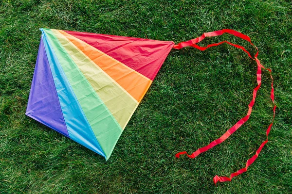 子供時代とレジャーゲームのコンセプト 緑の芝生や草の上で多色の凧のクローズアップ — ストック写真
