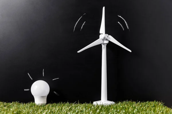 生態系 持続可能性の概念 風力タービンモデルの閉鎖と黒い背景の上の緑の芝生の電球の省エネ — ストック写真