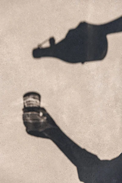 阴影和轮廓概念 从瓶子到杯子倒水的手的阴影 — 图库照片