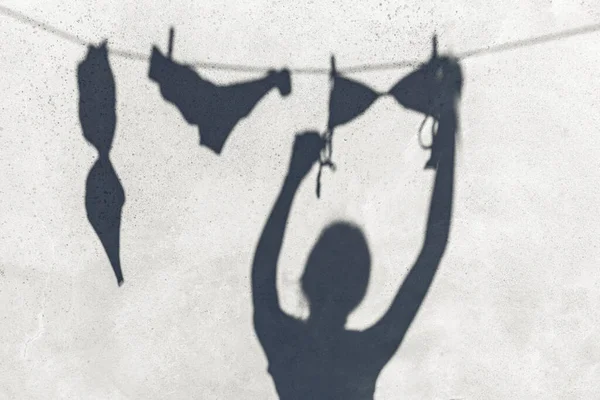 洗濯とシルエットのコンセプト ロープの上でランジェリーや水着をぶら下げ女性の影屋外 — ストック写真