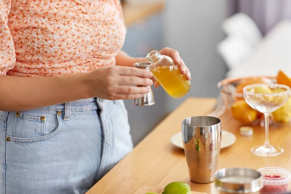 飲み物と人々のコンセプト ジッガーに酒やシロップを注ぐ女性の終わりと家庭用キッチンでカクテルを作る — ストック写真