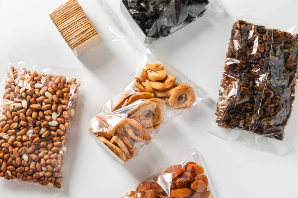 food storage, healthy eating and diet concept - close up of bags with dried fruits, nuts and cookies on white background
