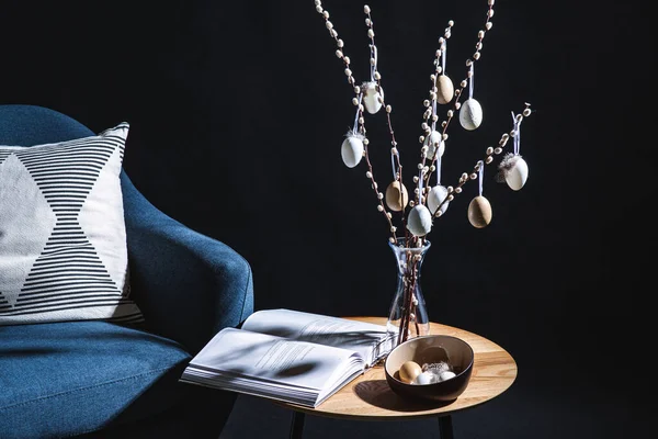 假日和家居装饰概念 在黑暗的房间里 用挂在桌上柳枝上的枕头和复活节彩蛋把现代蓝色椅子关上 — 图库照片
