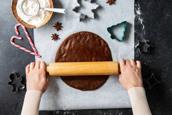 烹调和圣诞节概念 双手合拢 在厨房黑桌顶部用滚动销滚动姜饼面团 — 图库照片