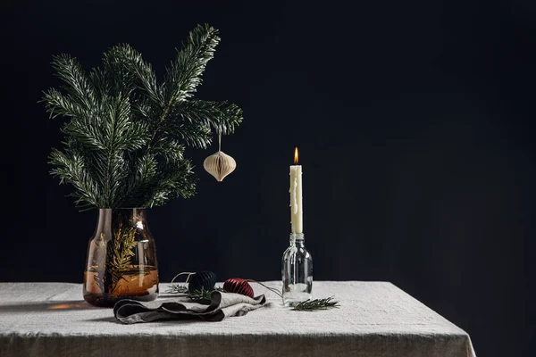 寒假和庆祝理念 用圣诞玩具和蜡烛在黑色背景的桌上点燃 关闭花瓶中的冷杉枝条 — 图库照片