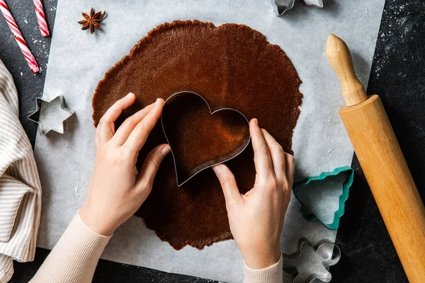 烹调和圣诞节概念 用模切姜饼面团在厨房黑桌顶部合拢双手 — 图库照片