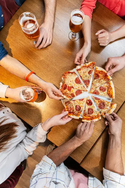 leisure, food and drinks, people and holidays concept - close up of friends eating pizza and drinking beer at restaurant or pub
