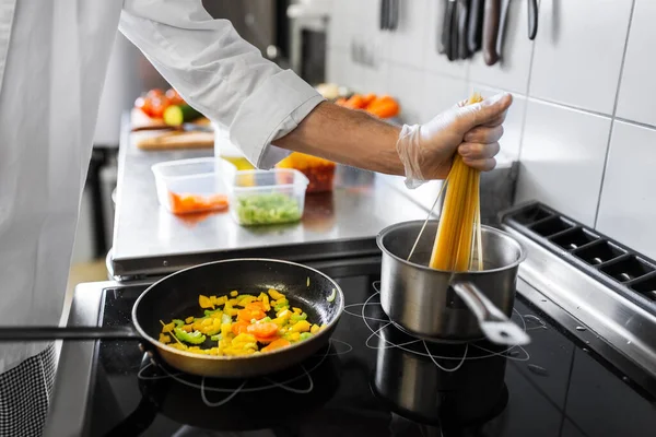 料理のコンセプト 男性シェフがスパゲッティパスタを調理し レストランキッチンで野菜を揚げる — ストック写真