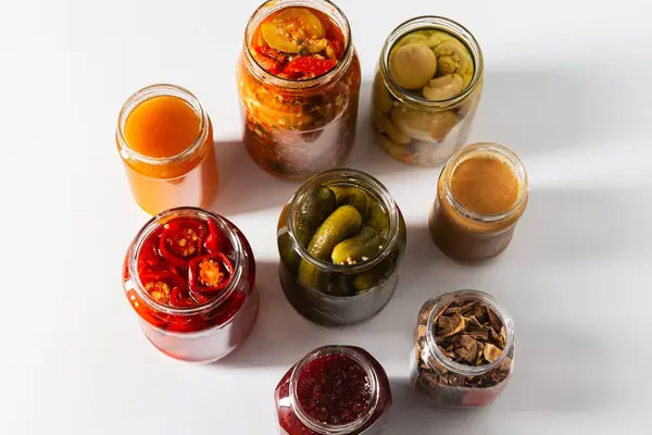 food, eating and preserve concept - close up of jars with preserves on white background