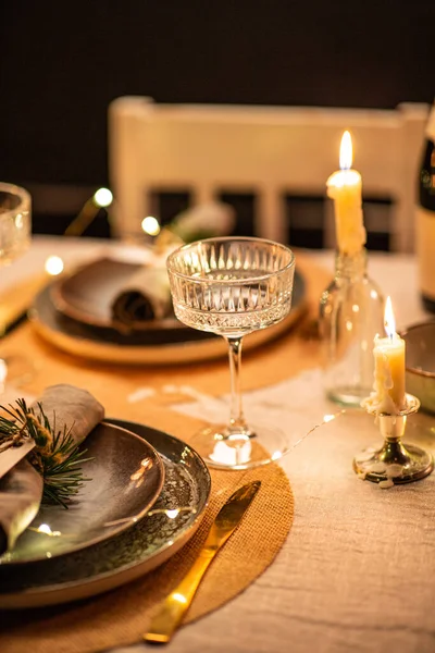 winter holidays, dinner party and celebration concept - close up of champagne saucer glass and scandinavian christmas table serving with burning candles at home at night