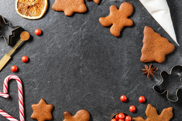 christmas, food cooking and winter holidays concept - close up of gingerbread cookies, molds, pastry bag and other ingredients on black table top at kitchen