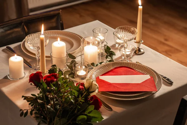 ディナーパーティー お祝いのコンセプト 赤いバラを提供するお祝いのテーブルの閉鎖 バレンタインデーの夜に家で愛のメッセージと燃えるろうそく — ストック写真