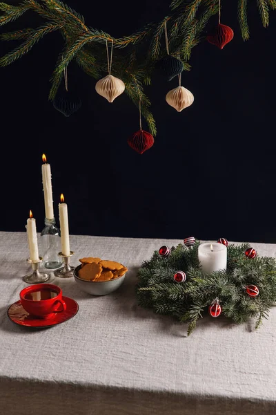 冬の休日やお祝いのコンセプト ブラックバック上のテーブル上のクリスマスリース ジンジャーブレッド ろうそくのクローズアップ — ストック写真