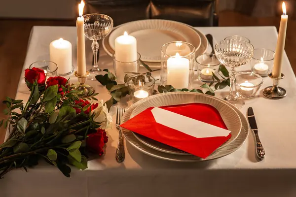 holidays, dinner party and celebration concept - close up of festive table serving with red roses, love message and burning candles at home at night on valentines day
