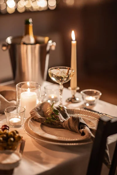 holidays, dinner party and celebration concept - close up of festive table serving with champagne bottle in ice bucket and candles burning at home on valentines day