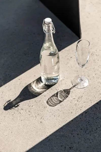 Objekt Und Getränkekonzept Flasche Wasser Und Glas Auf Sonnigem Boden lizenzfreie Stockfotos